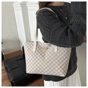 Close-up of off-white tote bag with M-letter monogram and elegant gold logo plate