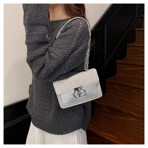 Detail of silver glitter shoulder bag featuring metal interlocking buckle and chain strap