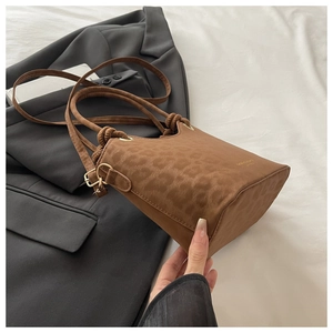 Detail of leopard print bucket bag with suede texture and adjustable shoulder strap