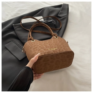 Detailed view of brown leopard print handbag with gold logo on white linen backdrop