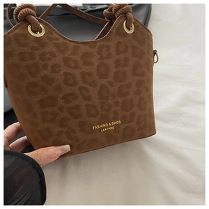 Detail of leopard print handbag featuring matte suede texture and gold eyelet accents