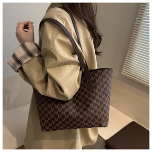 Detail of large tote bag with brown M-letter pattern and elegant long shoulder handles