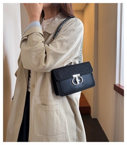 Detail of a black sequin crossbody bag with a silver CD buckle on a stylish beige coat