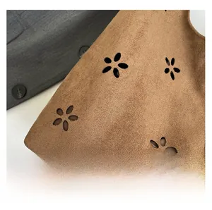 Detailed macro shot of brown suede tote bag with laser-cut hollow floral patterns