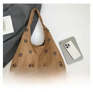 Detail of laser-cut flower pattern on a brown suede shoulder bag for women