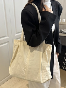 Minimalist beige nylon tote bag with wide straps shown on model for casual commuting use