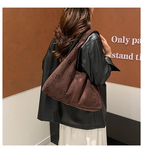 Close-up of laser-cut floral patterns on dark brown suede tote bag with shoulder strap