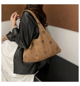 Macro detail of brown suede shoulder bag featuring intricate laser-cut floral patterns