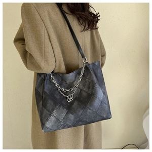 Detail of vintage quilted tote bag featuring silver chains and a metallic B pendant
