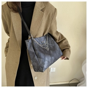 Close-up of diamond-stitched tote bag with heart chain detail worn on shoulder