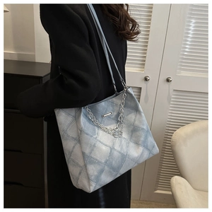 Detail of light blue quilted tote bag with silver chains and diamond stitching on shoulder