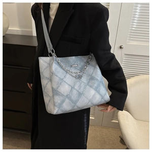 Close-up of light blue quilted denim tote bag featuring silver chain and B pendant