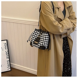 Detail of retro checkerboard bucket bag with black leather drawstring and gold buckle