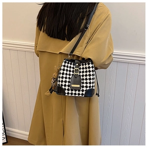 Model view of black and white checkerboard bucket bag with drawstring and gold buckle