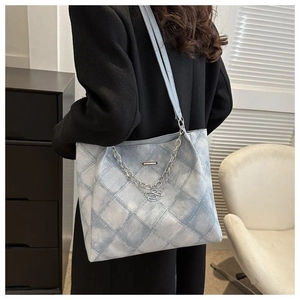 Detail of light blue quilted tote bag with silver chain and heart pendant accessory