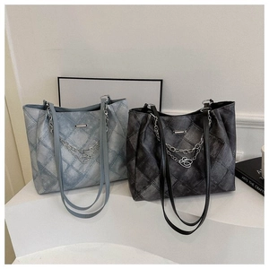 Close-up of quilted tote bags in blue and dark grey denim texture with metal chain detail