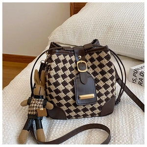 Close-up of quilted pattern bucket bag with a cute rabbit plush charm detail