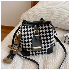 Detail of checkered tweed bucket bag with leather trim and cute knit bunny charm