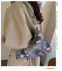 Détail du sac seau matelassé avec motifs nuages et arc-en-ciel porté par un mannequin