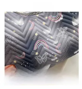 Gros plan sur le tissu matelassé d'un sac à bandoulière avec motifs arc-en-ciel et papillons