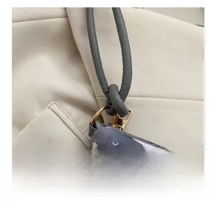 Gros plan d'un sac seau gris matelassé avec imprimé arc-en-ciel et anneaux en métal doré
