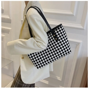 Side view of checkered tweed tote bag with black shoulder straps and gold rivet accents