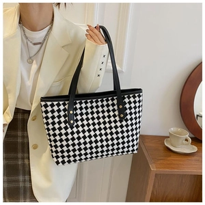 Detail of checkered tote bag fabric texture with black leather straps and gold studs