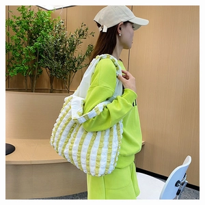 Texture détaillée du sac cabas rayé jaune et blanc en tissu popcorn porté par un mannequin