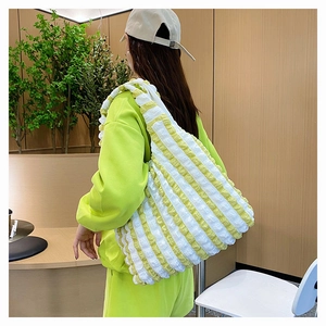 Vue détaillée du sac cabas plissé à rayures jaunes et blanches porté par un modèle