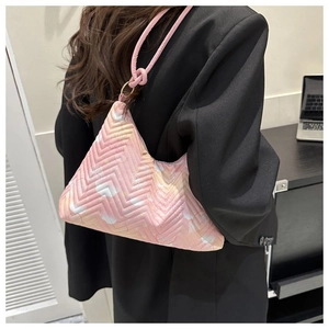 Détail d'un sac à bandoulière rose matelassé avec surpiqûres en V sur blazer