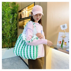 Détail du sac cabas à rayures vertes et blanches avec texture gaufrée dans un café