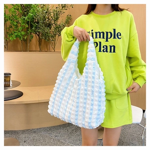 Détail de la texture d'un sac cabas en seersucker à rayures bleues et blanches au café