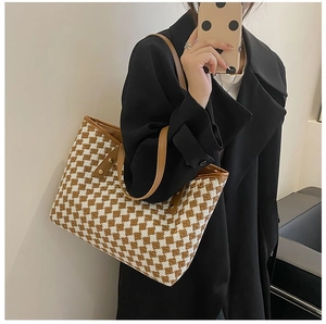 Mirror selfie showing the large woven tote bag with brown leather trim and metal rivets