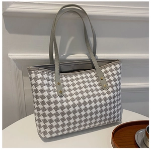 Detail view of large houndstooth tote bag with grey leather straps and gold rivets