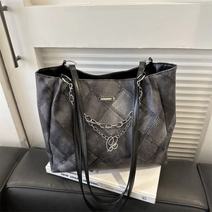 Grey quilted denim tote bag with metal chains and letter pendant on a modern background