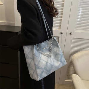 Light blue quilted denim tote bag with silver chain and metal buckle shown on shoulder
