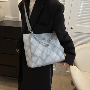 Quilted light blue tote bag with metallic chain and letter B charm shown on model