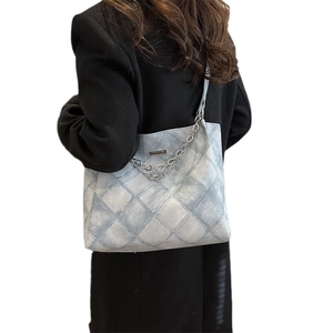 Quilted light blue denim tote bag with chain strap shown on model back view