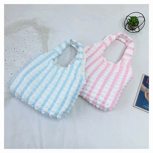 Détail de sacs cabas en seersucker rose et bleu montrant la texture gaufrée et les anses souples