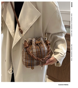 Detail of vintage wool plaid bucket bag with leather drawstring and braided handle