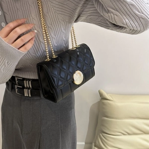Détail du sac bandoulière matelassé noir avec chaîne dorée et fermoir texturé rond