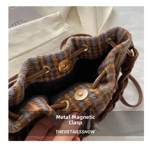 Close-up of matte gold magnetic snap closure and plaid wool fabric on bucket bag