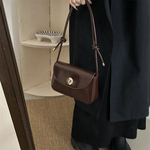 Detail of vintage brown leather crossbody bag with gold knob lock and knotted strap