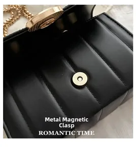 Gros plan du fermoir magnétique doré sur le sac bandoulière en cuir noir matelassé