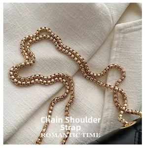 Détail d'une bandoulière en chaîne dorée brillante sur un sac en cuir noir matelassé