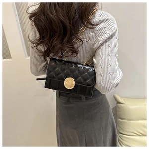 Sac bandoulière matelassé noir avec chaîne dorée porté par un mannequin