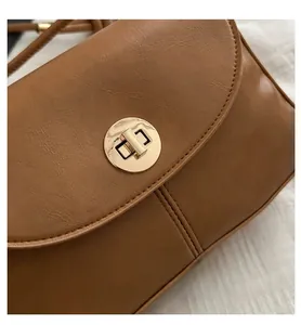 Detail of vintage brown leather handbag featuring a golden round twist lock buckle