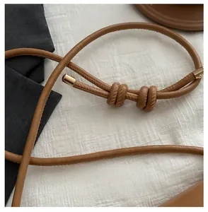 Detail of caramel brown leather shoulder strap with decorative knot and gold hardware