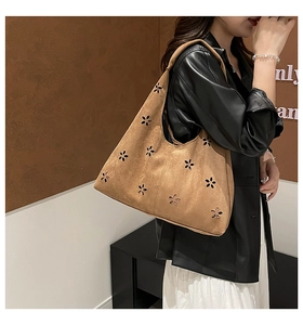 Close-up of laser-cut floral patterns on brown faux suede large capacity tote bag