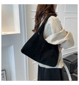Black velvet tote bag featuring intricate laser-cut floral patterns worn by a model